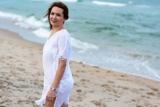 Woman basking in summer wearing a white linen beach cover-up dress.