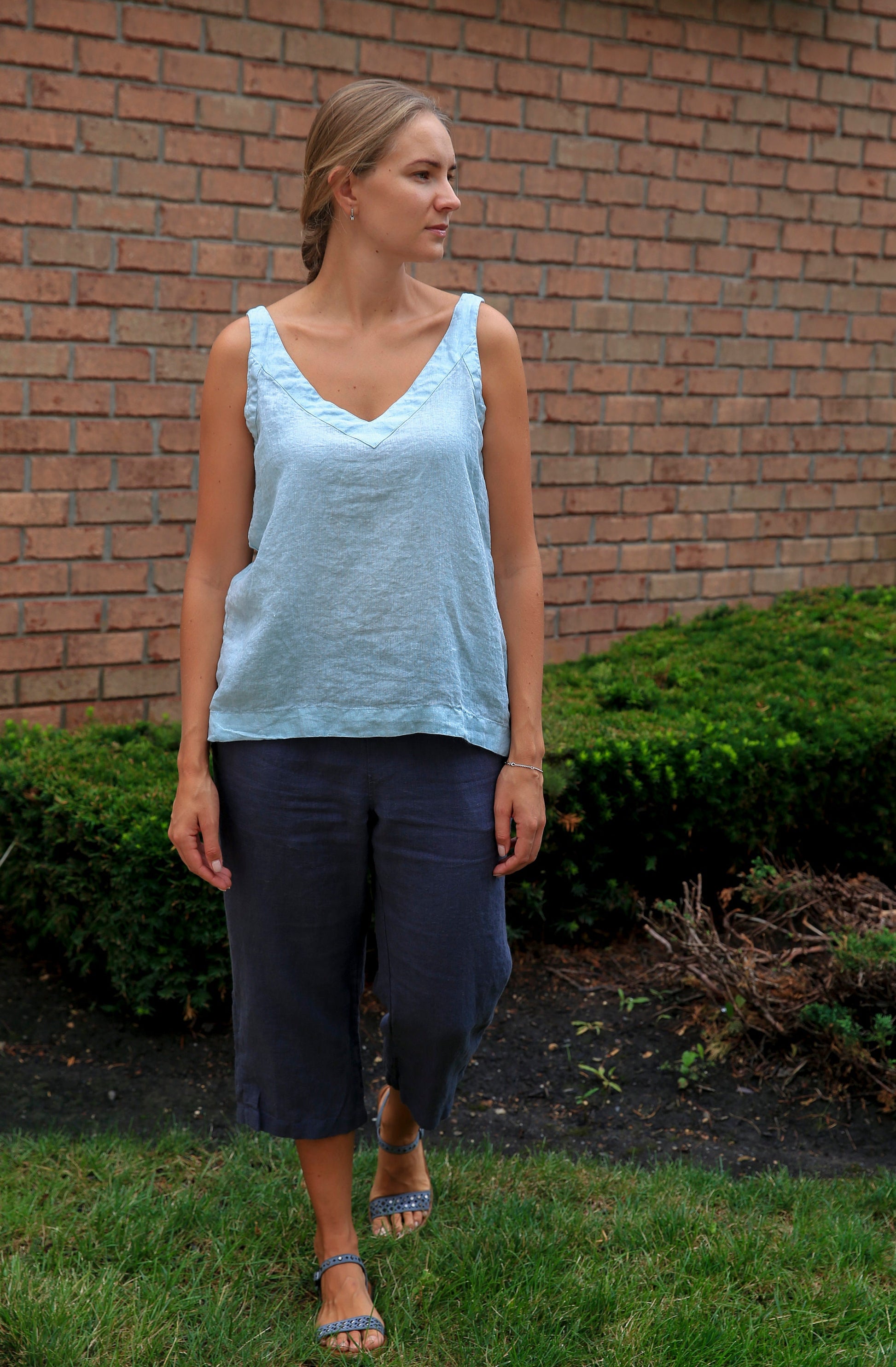 Woman in a relaxed setting wearing a V-neck linen tank in a beautiful dusty rose shade