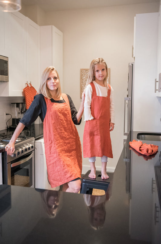 Young woman and a young girl wearing matching linen aprons 