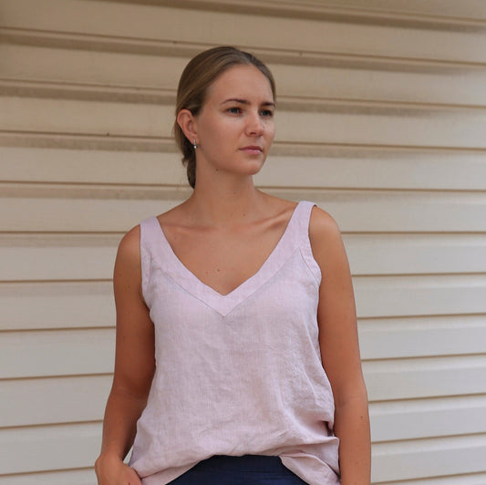Woman showcasing a dusty rose linen V-neck tank top with a natural texture