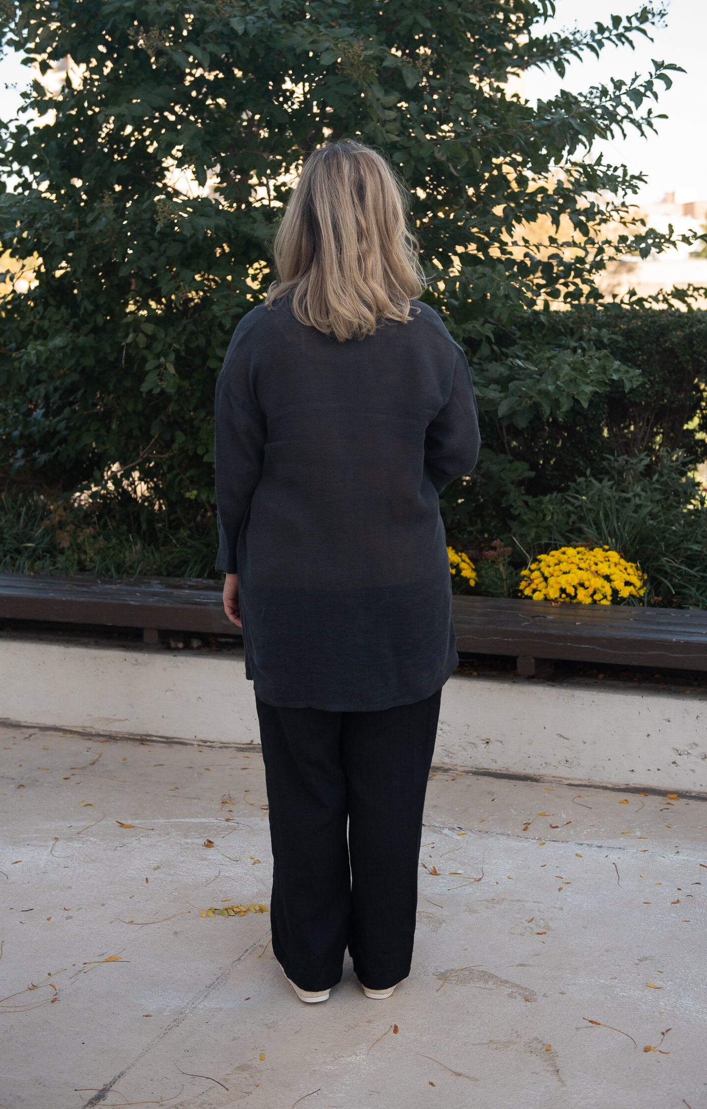 Woman in a cozy setting wearing an oversized boho linen cardigan with pockets view from rear