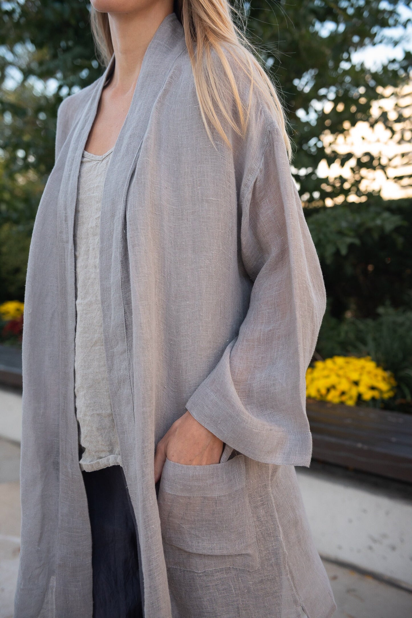 Woman in a cozy setting wearing an oversized boho linen cardigan with pockets light grey