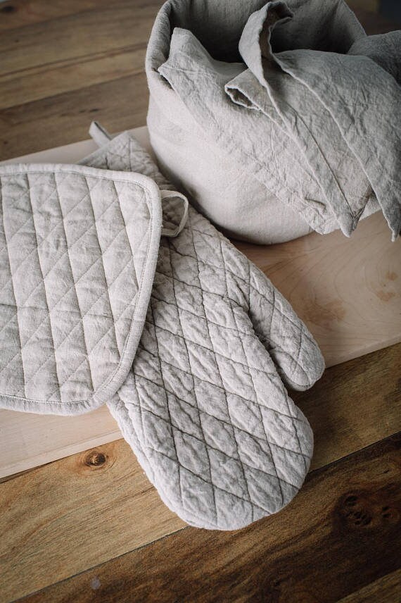 Baking essentials: Woman with linen kitchen gloves and pot holders.