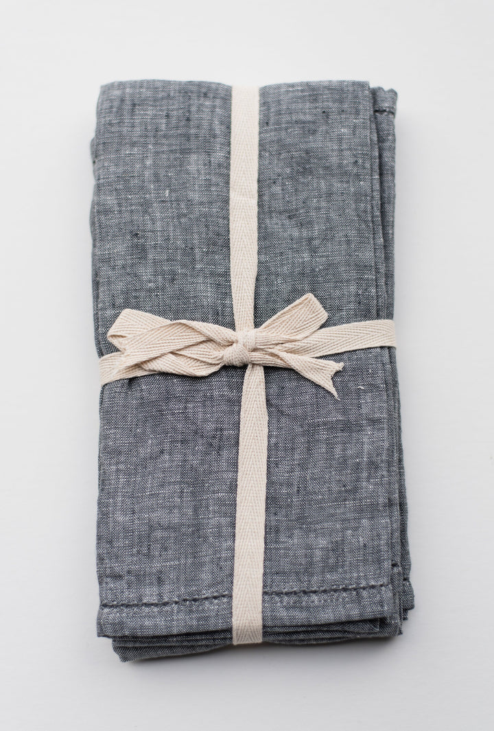 A bundle of four stonewashed linen napkins tied with a rustic string.