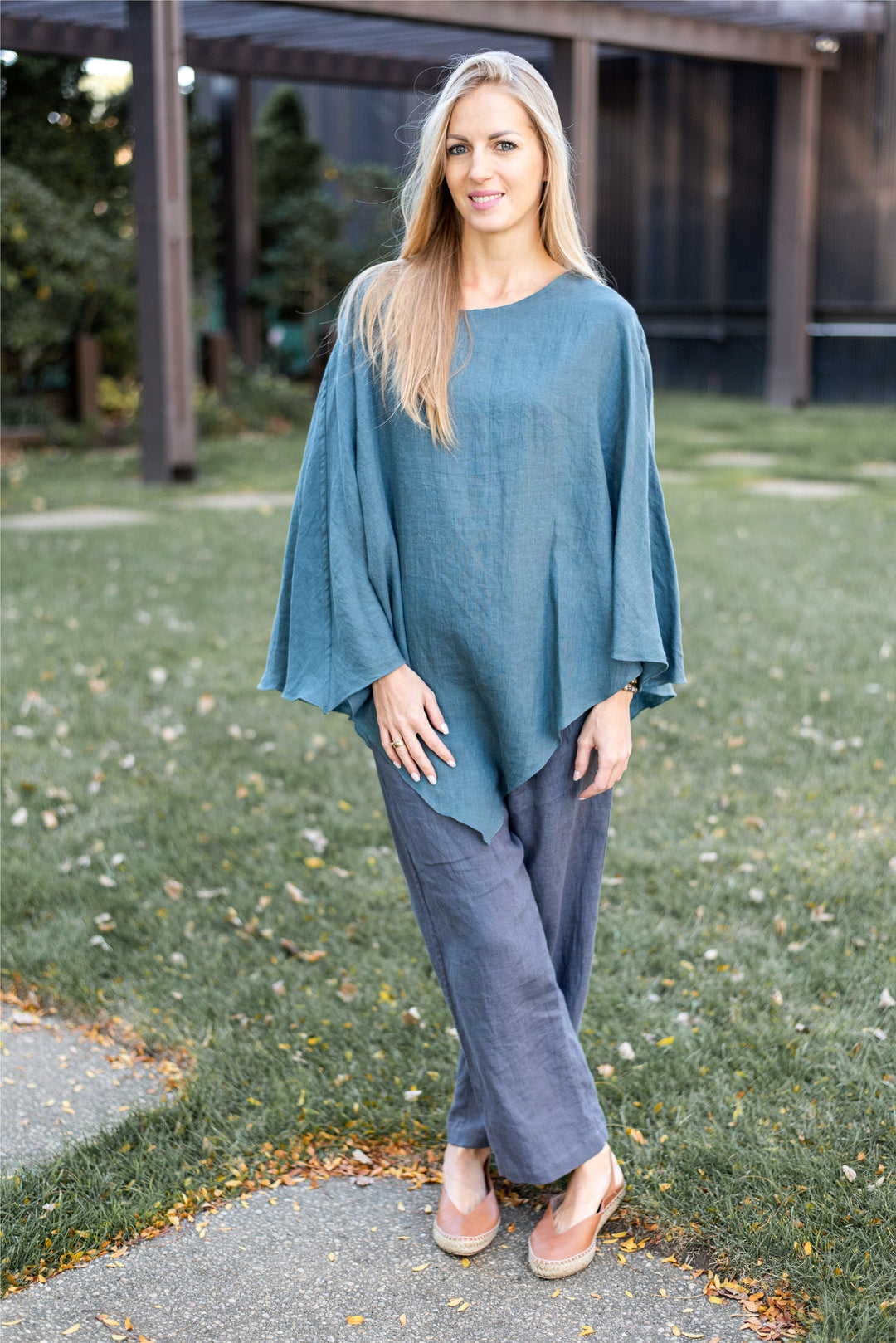 Woman draped in a linen poncho wrap, front view, showcasing its elegant drape.