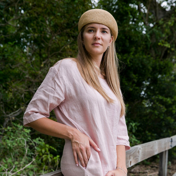 Woman in a dusty rose linen tunic dress, showcasing its oversized style.