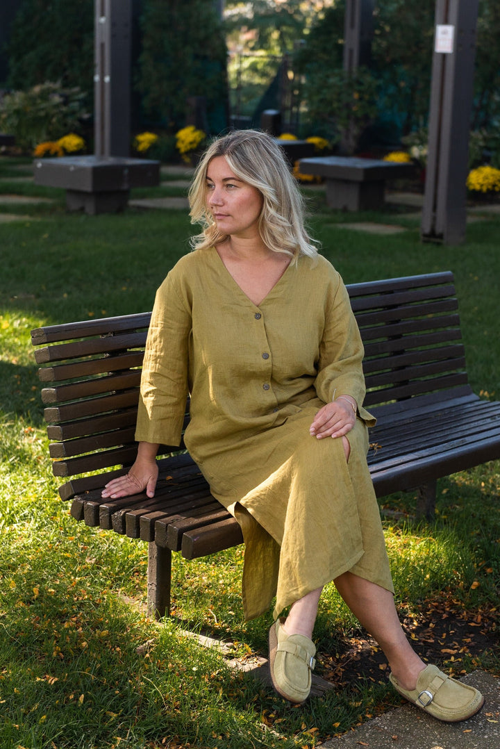 Woman draped in a mustard yellow linen duster, radiating effortless chic.