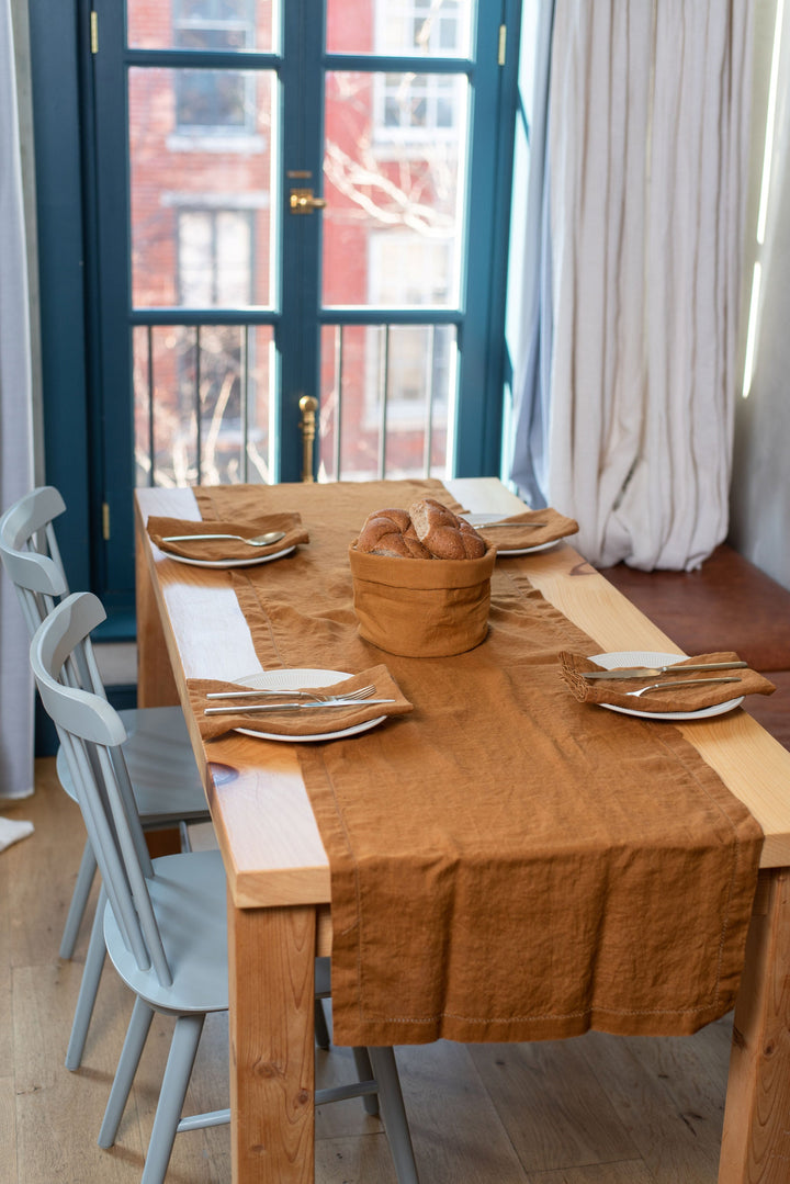 Artistic fold of pre-washed linen table runner on a rustic table.