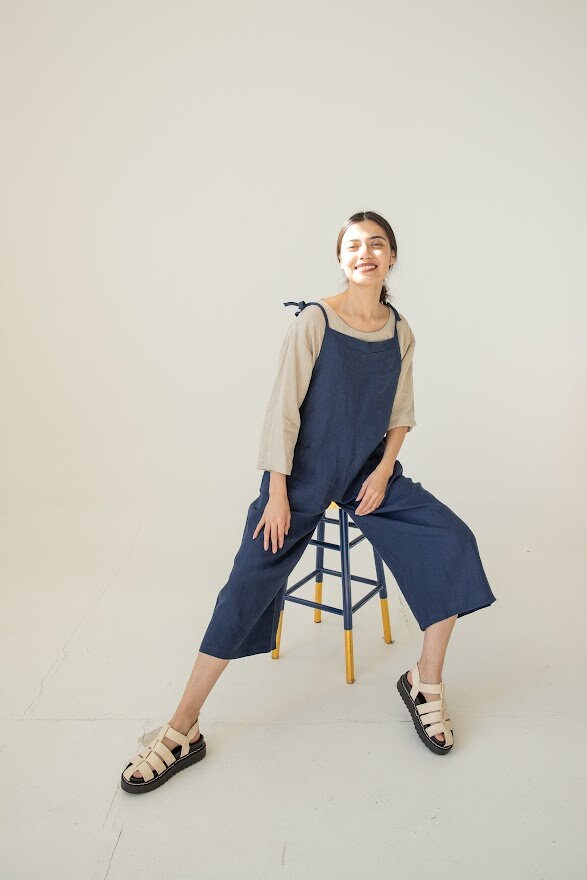 Woman lounging, focusing on the romper's deep functional pockets.